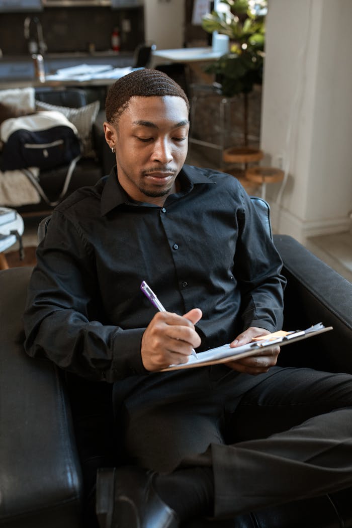 Professional man writing notes on clipboard during interview in office.